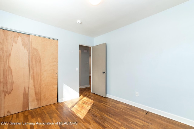 unfurnished bedroom featuring a closet, baseboards, and wood finished floors