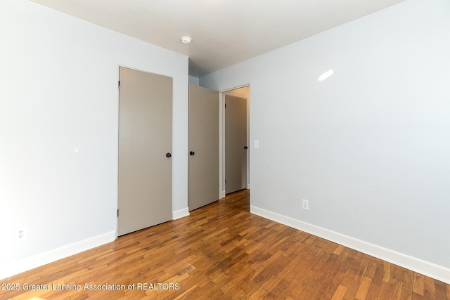 unfurnished room featuring baseboards and wood finished floors