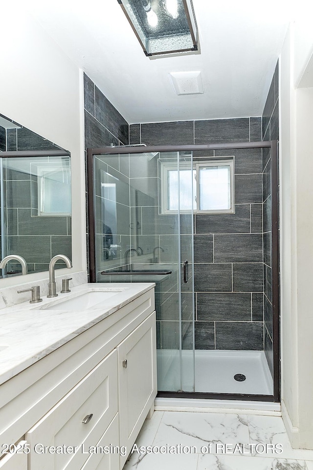 full bath featuring marble finish floor, a stall shower, and vanity