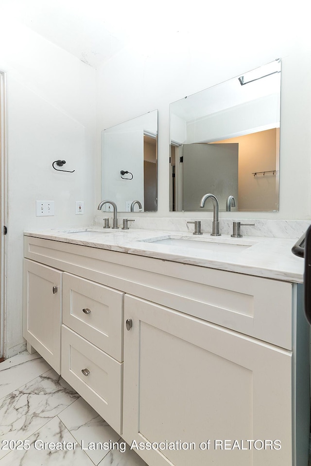 full bathroom with double vanity, marble finish floor, and a sink