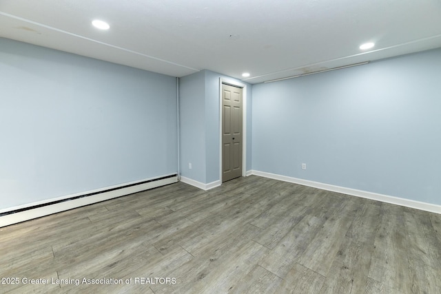 finished basement featuring recessed lighting, a baseboard radiator, light wood-style flooring, and baseboards