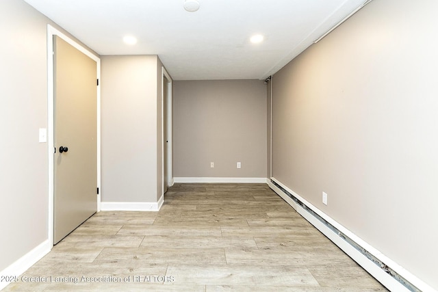 spare room featuring light wood-type flooring, recessed lighting, a baseboard radiator, and baseboards