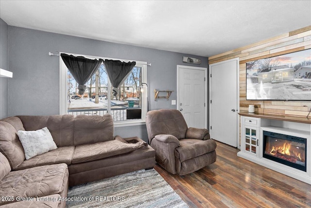 living room with dark wood-type flooring and a glass covered fireplace