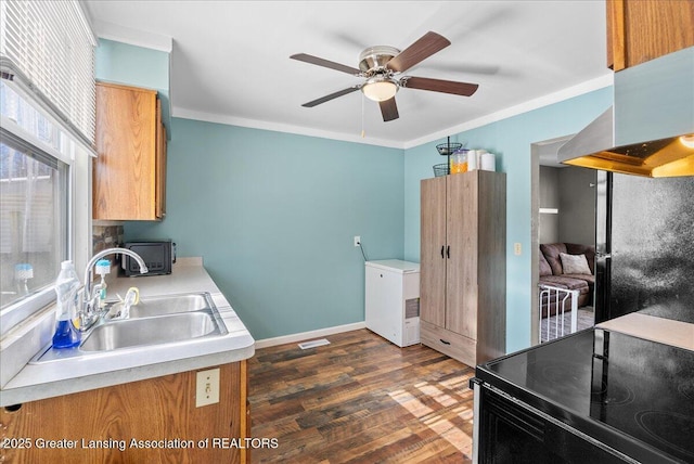 kitchen with range with electric cooktop, a sink, light countertops, ornamental molding, and dark wood finished floors