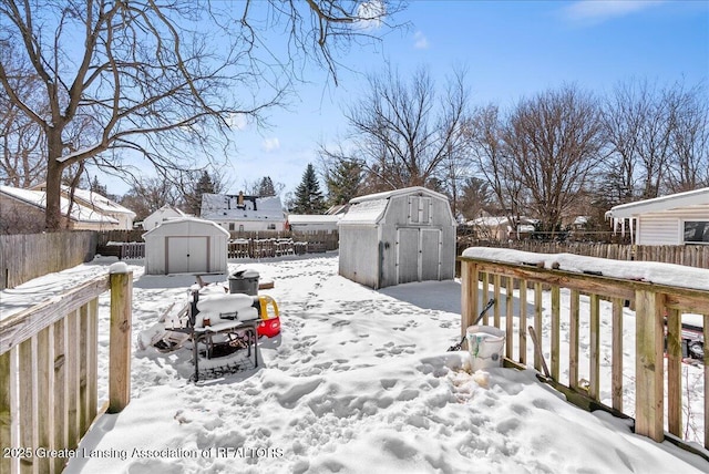 snowy yard featuring an outbuilding, a fenced backyard, and a storage shed