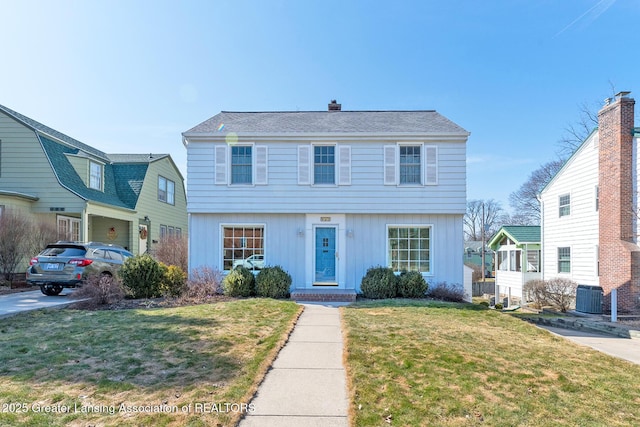 colonial-style house with central AC, a chimney, and a front yard