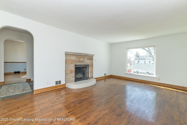 unfurnished living room with visible vents, wood-type flooring, and baseboards