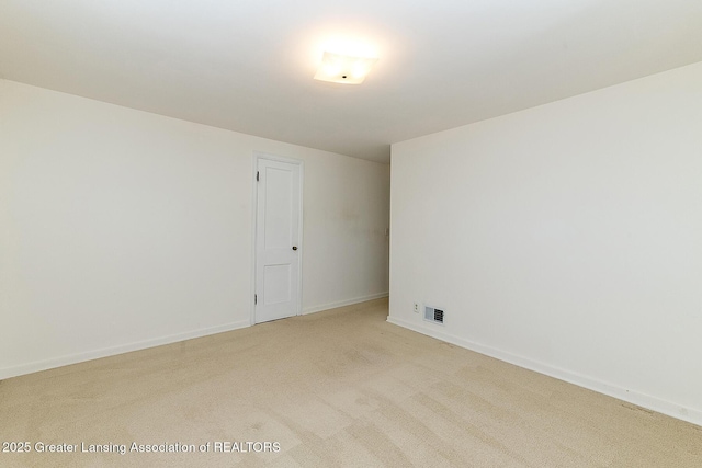 spare room featuring visible vents, light colored carpet, and baseboards