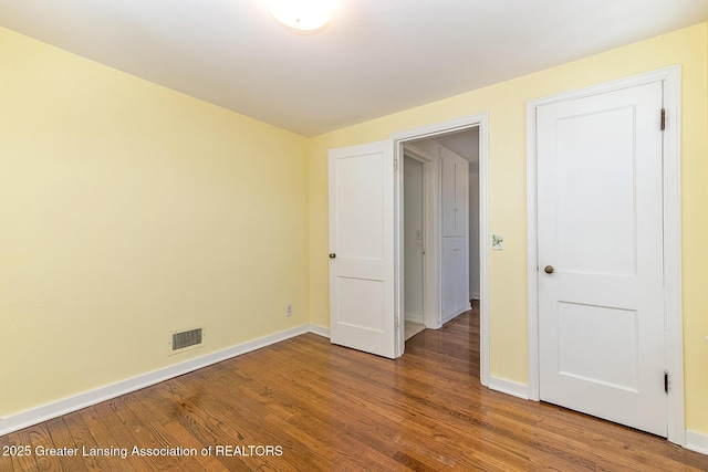 unfurnished bedroom with visible vents, baseboards, and wood finished floors