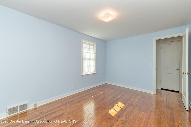 spare room featuring visible vents, baseboards, and hardwood / wood-style floors