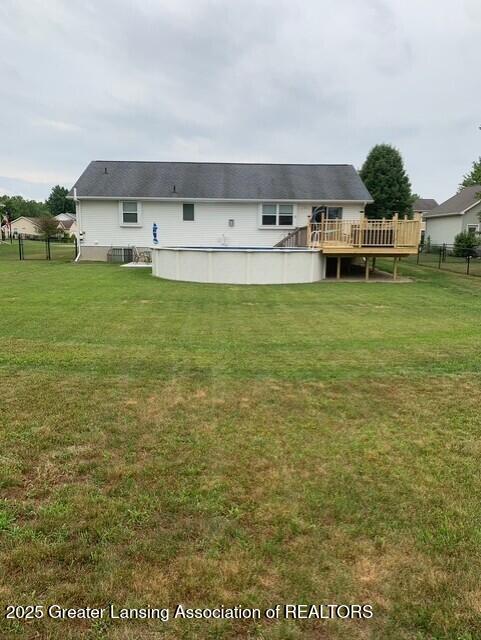 back of property with a lawn, a deck, a swimming pool, and fence