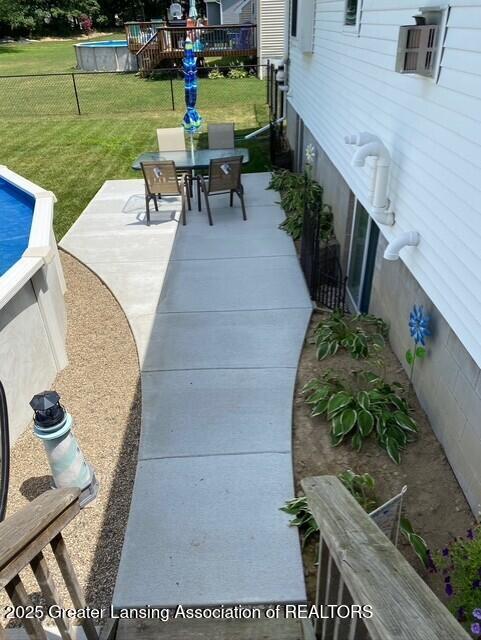 view of patio featuring outdoor dining area, fence, and an outdoor pool