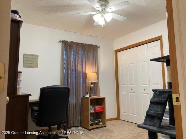 office area with a textured ceiling, ceiling fan, baseboards, and light colored carpet