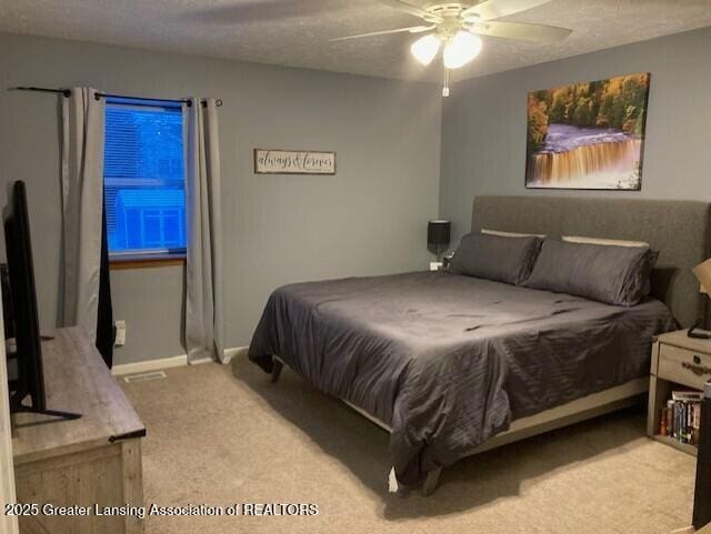 carpeted bedroom with a textured ceiling, ceiling fan, and baseboards