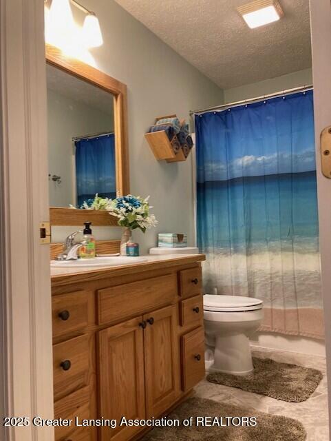 full bathroom with a shower with shower curtain, toilet, vanity, and a textured ceiling