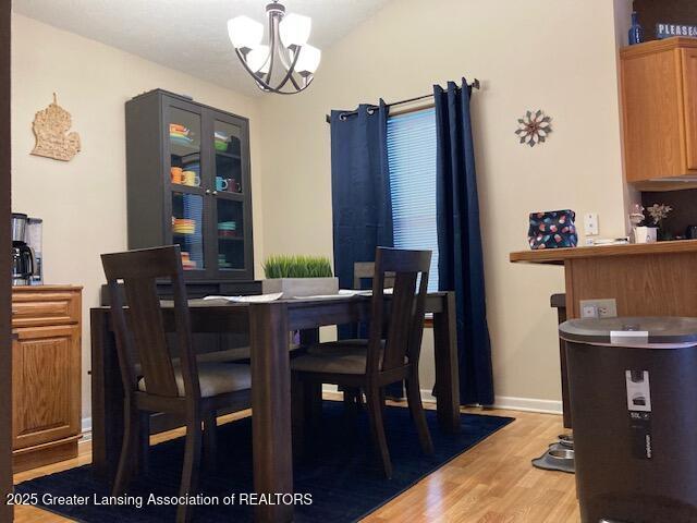 dining room with light wood-style flooring, a chandelier, and baseboards