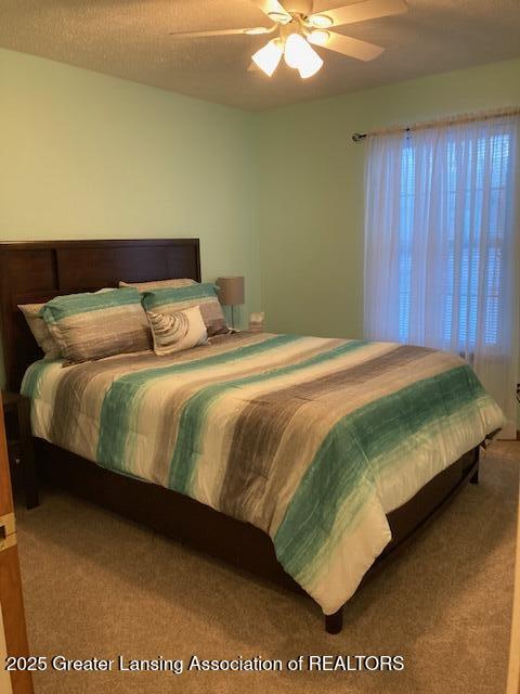 bedroom with carpet, a ceiling fan, and a textured ceiling