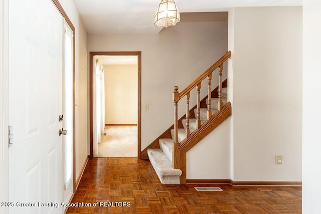 foyer featuring visible vents, stairway, and baseboards