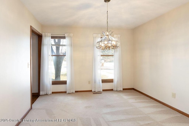 empty room with light carpet, baseboards, and an inviting chandelier