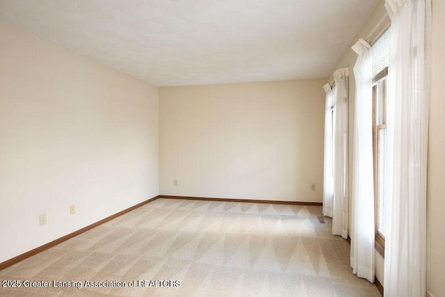 empty room featuring baseboards and light colored carpet