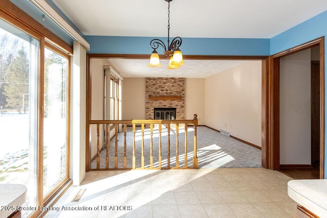 interior space featuring baseboards, visible vents, tile patterned floors, a brick fireplace, and a chandelier