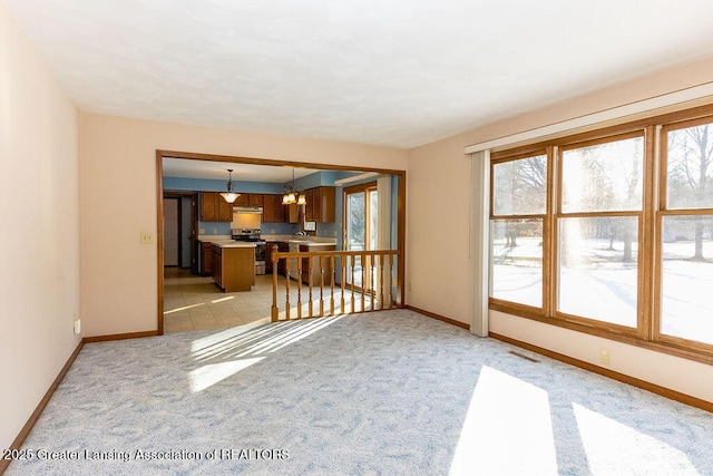 unfurnished living room with baseboards, visible vents, and light colored carpet