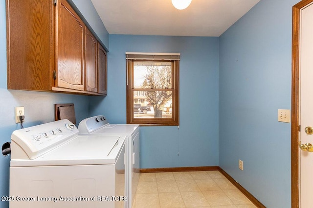 clothes washing area with washing machine and dryer, cabinet space, and baseboards