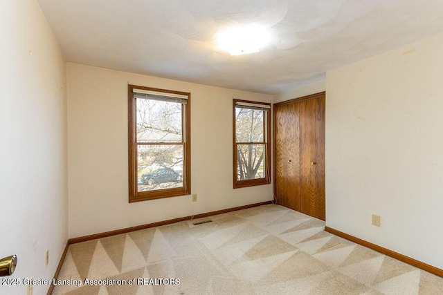 unfurnished room featuring baseboards, visible vents, and light colored carpet