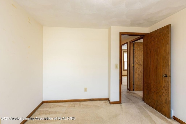 empty room featuring light carpet and baseboards