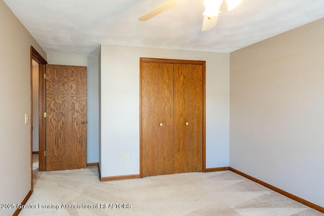 unfurnished bedroom featuring baseboards, a closet, and light colored carpet