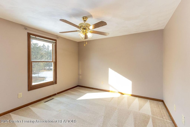 spare room featuring baseboards, a ceiling fan, visible vents, and light colored carpet