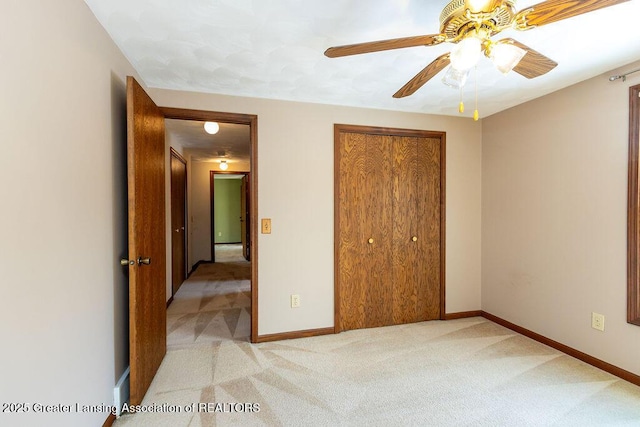 unfurnished bedroom with a ceiling fan, a closet, light carpet, and baseboards