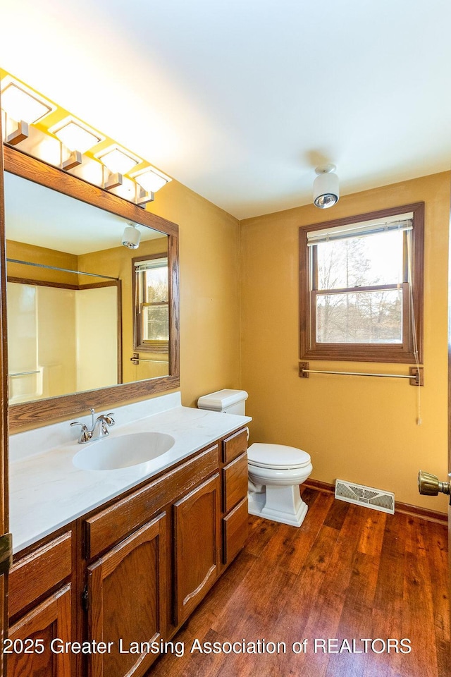 full bath with toilet, wood finished floors, vanity, visible vents, and baseboards