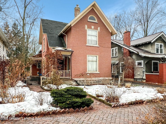 view of front of home with brick siding, a chimney, and roof with shingles