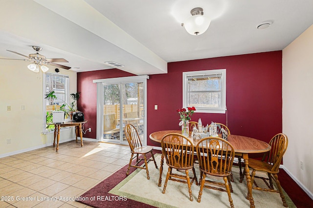 dining area with light tile patterned floors, an accent wall, visible vents, and baseboards