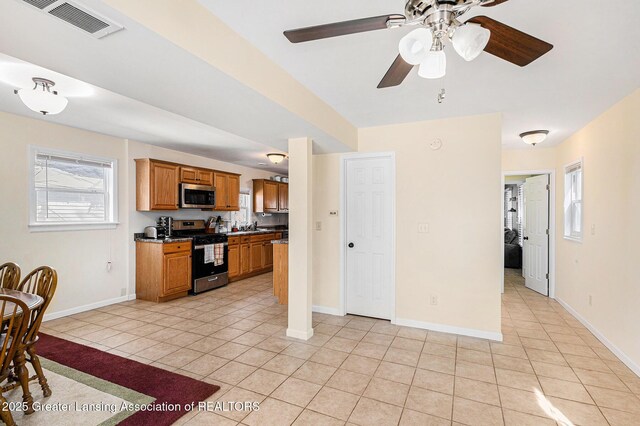 kitchen featuring brown cabinets, light tile patterned floors, dark countertops, visible vents, and appliances with stainless steel finishes