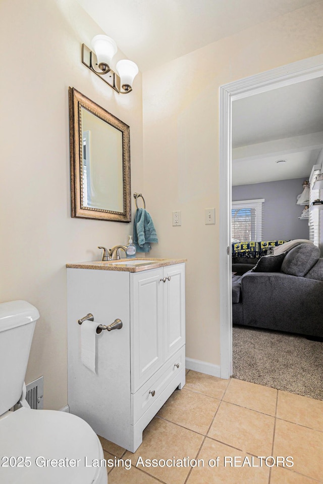 half bath with tile patterned flooring, toilet, connected bathroom, vanity, and baseboards