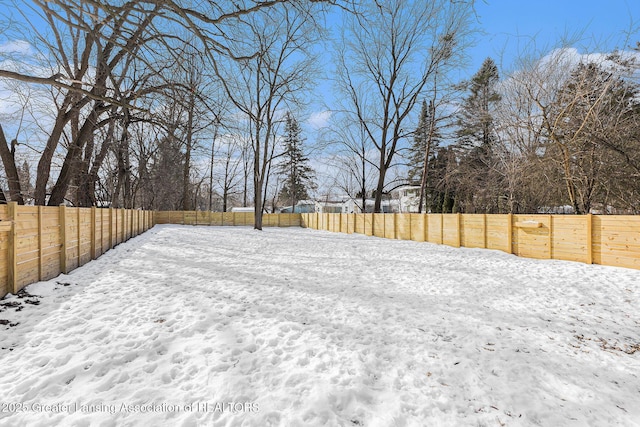 yard layered in snow with a fenced backyard