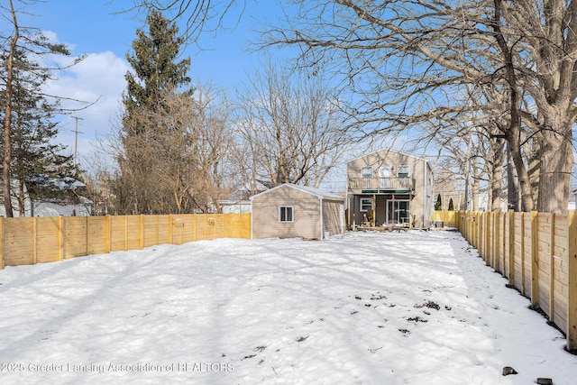 yard layered in snow with a storage unit, an outdoor structure, and a fenced backyard