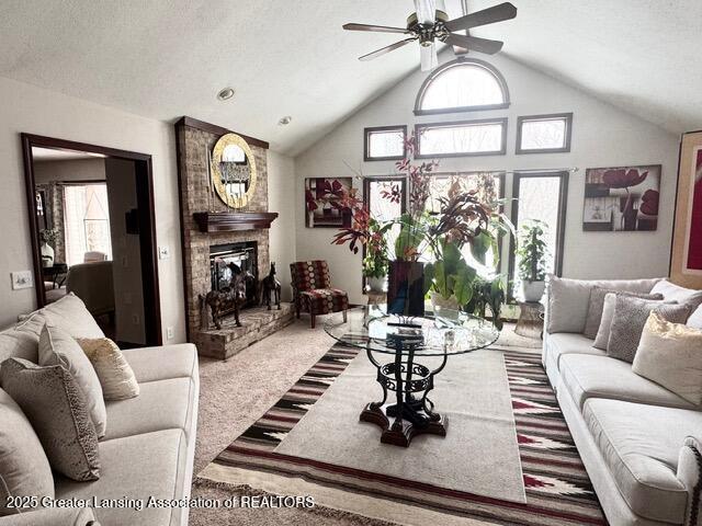 carpeted living room with a ceiling fan, a fireplace, a textured ceiling, and high vaulted ceiling