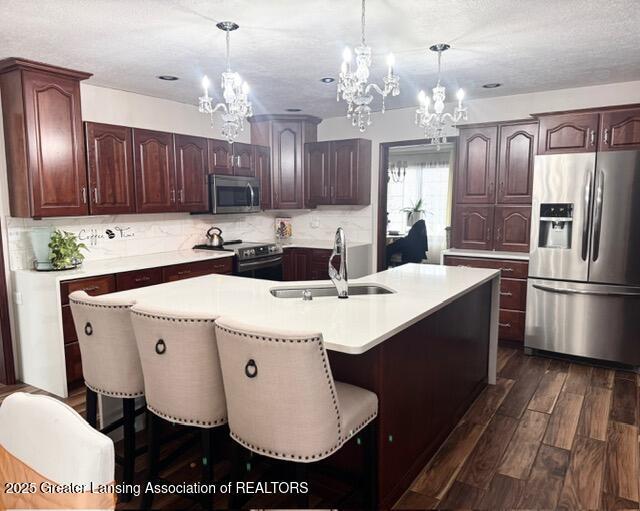 kitchen with stainless steel appliances, tasteful backsplash, dark wood-style flooring, and a sink