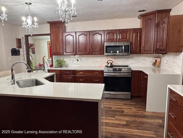 kitchen featuring stainless steel appliances, a sink, light countertops, and decorative backsplash