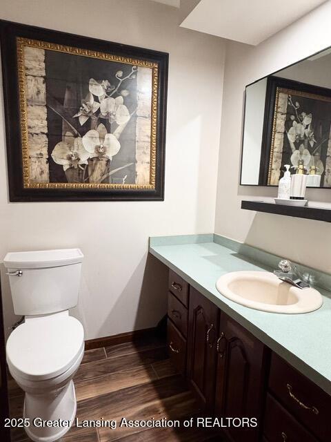 bathroom with baseboards, vanity, toilet, and wood finished floors