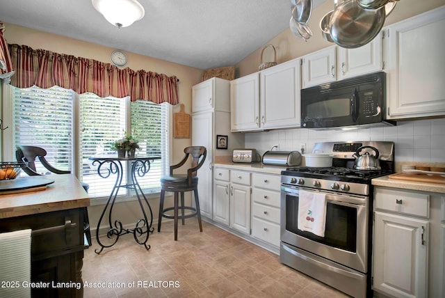 kitchen with gas range, white cabinetry, black microwave, and light countertops