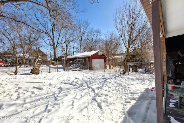 yard layered in snow with an outbuilding and fence