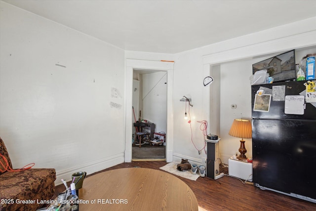 bedroom with dark wood-style flooring, freestanding refrigerator, and baseboards