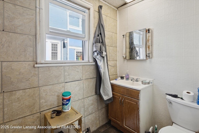 bathroom with tile walls, vanity, and toilet