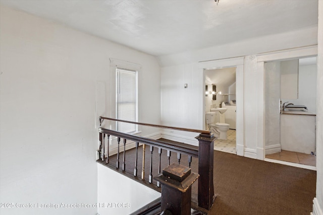 hallway featuring carpet floors, a sink, an upstairs landing, baseboards, and washer and clothes dryer