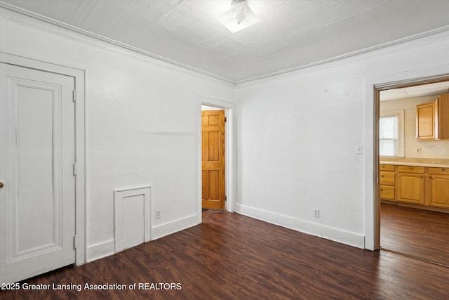 unfurnished bedroom with dark wood-style floors, baseboards, and crown molding