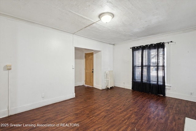 unfurnished room with a textured ceiling, dark wood-type flooring, baseboards, ornamental molding, and radiator heating unit